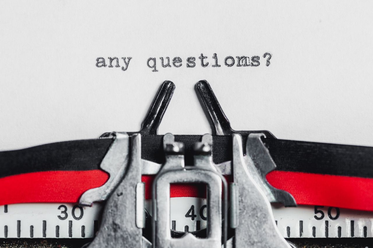 "any questions?" written on a paper that is on a typewriter machine