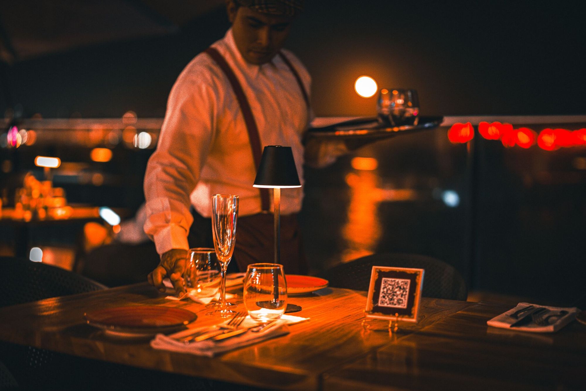 a waiter setting a table with a QR code