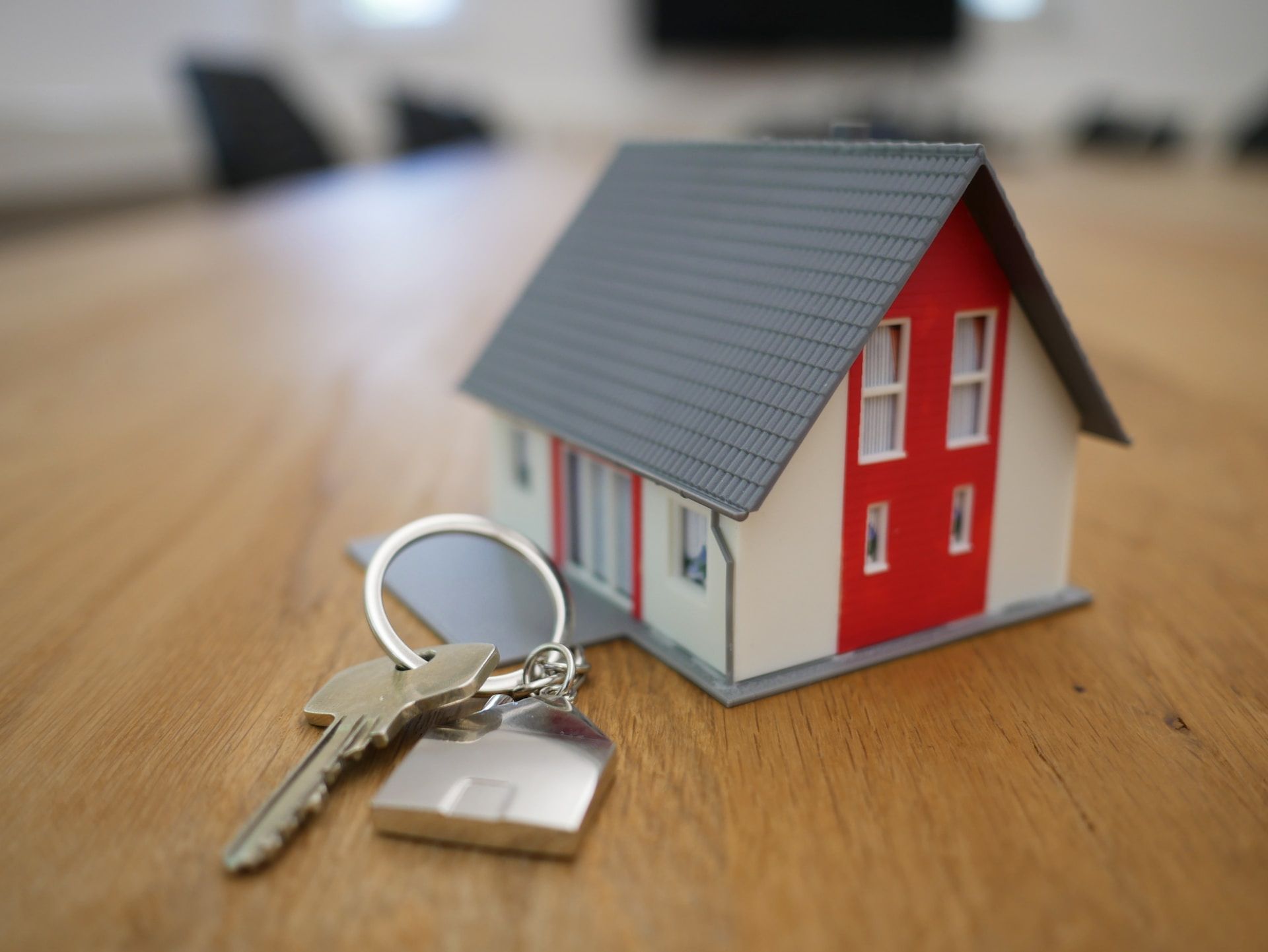 white and red wooden house next to keys on a table
