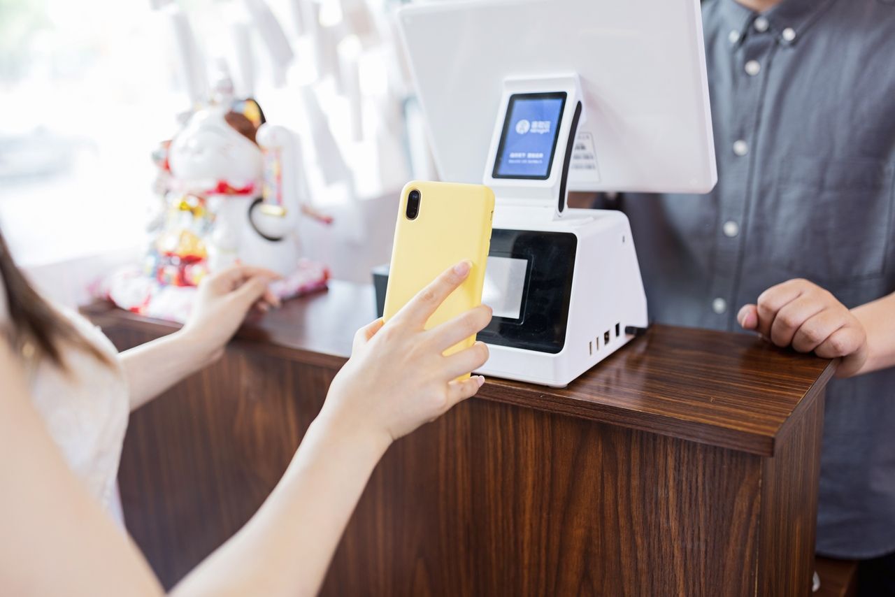 a woman scanning a QR code with a phone that has yellow case