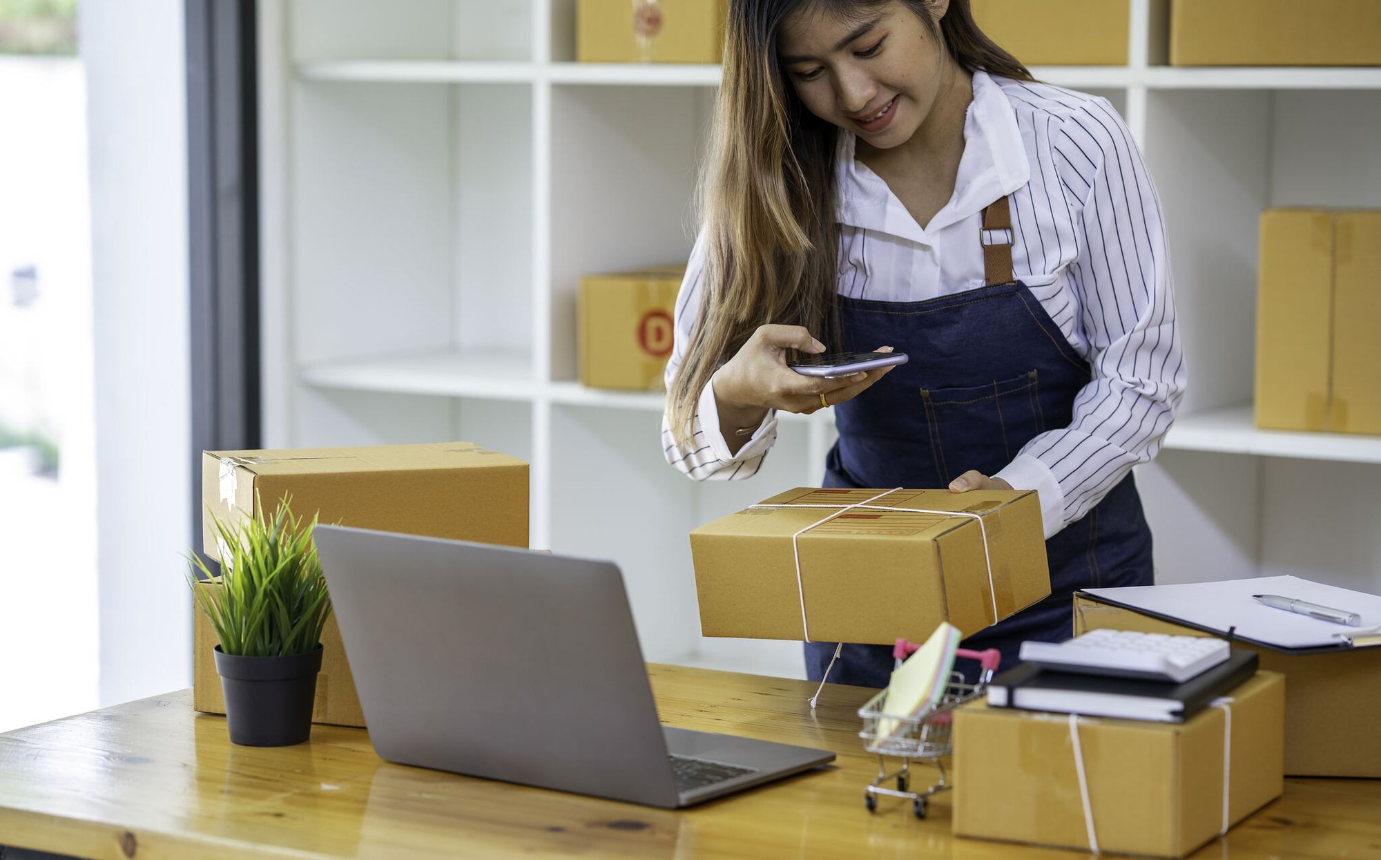 a smiling woman scanning a QR on a package, to manage inventory