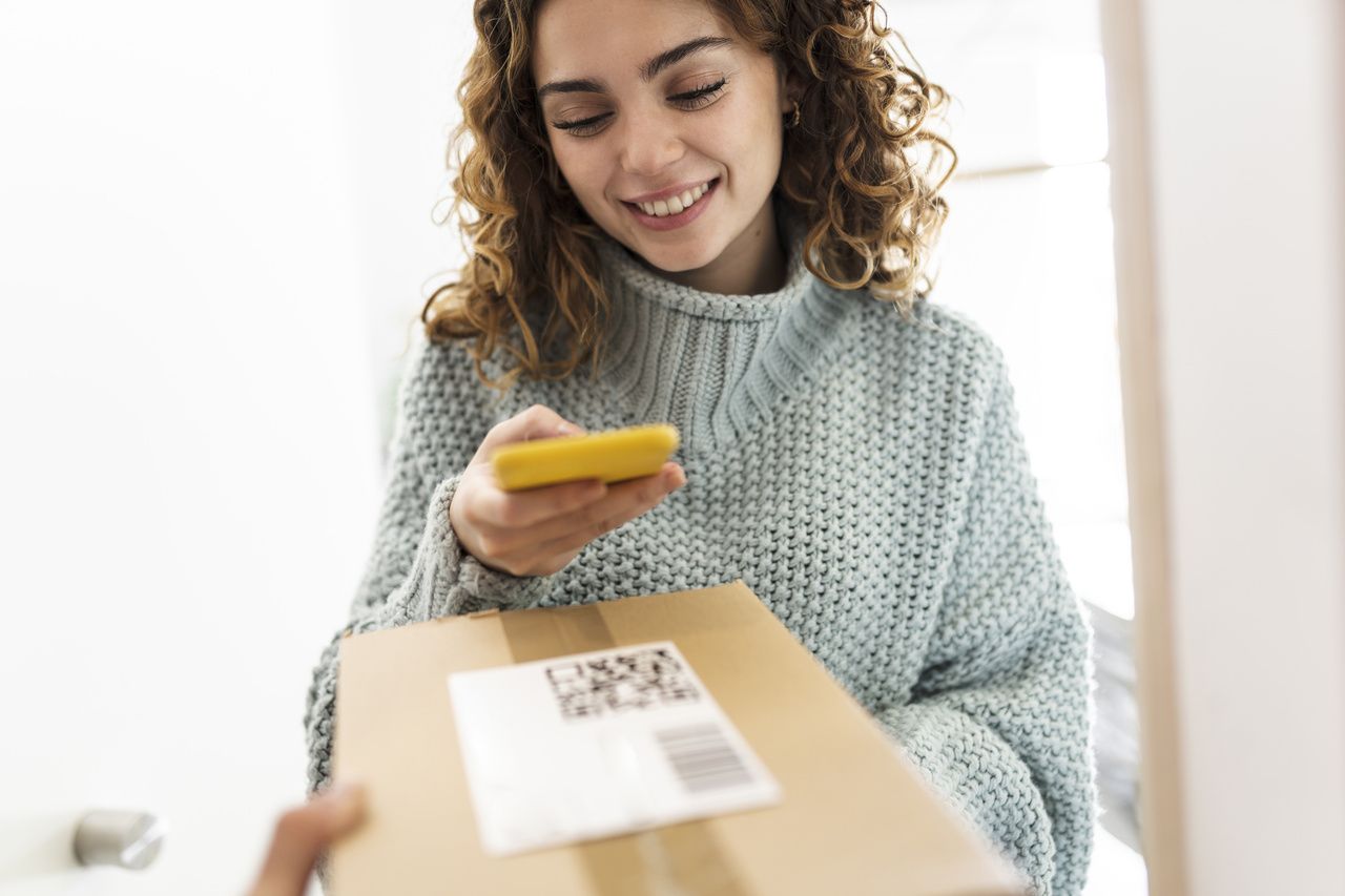 a girl smiling and scanning a QR code on a package