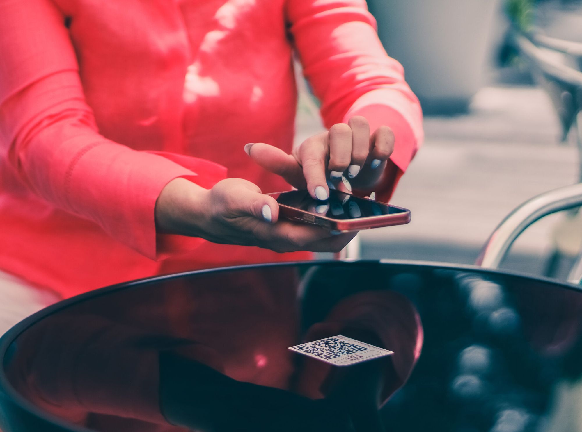 hands of a young woman scanning a QR code on a table