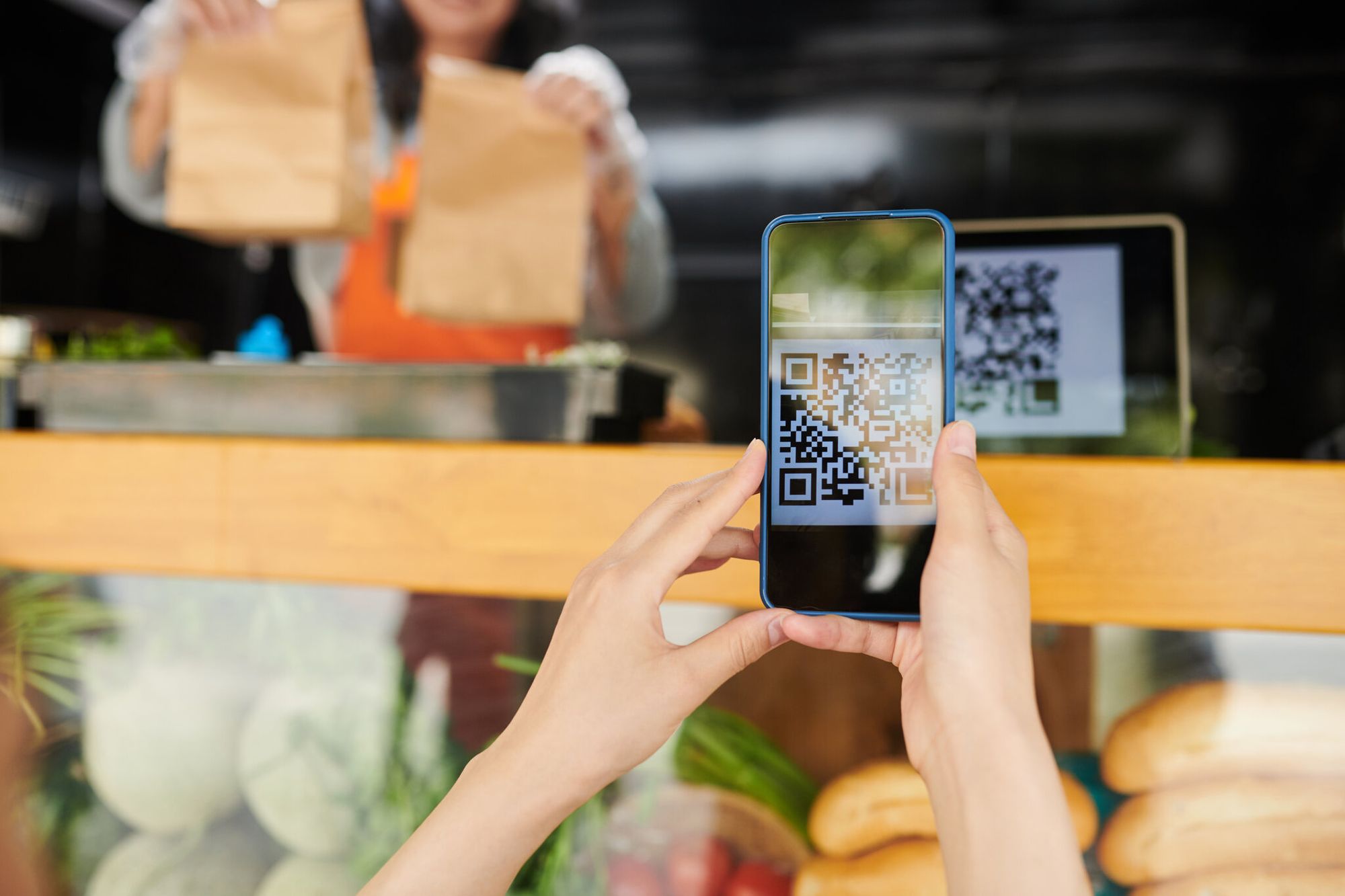 a hand scanning a QR code with a phone at a bakery