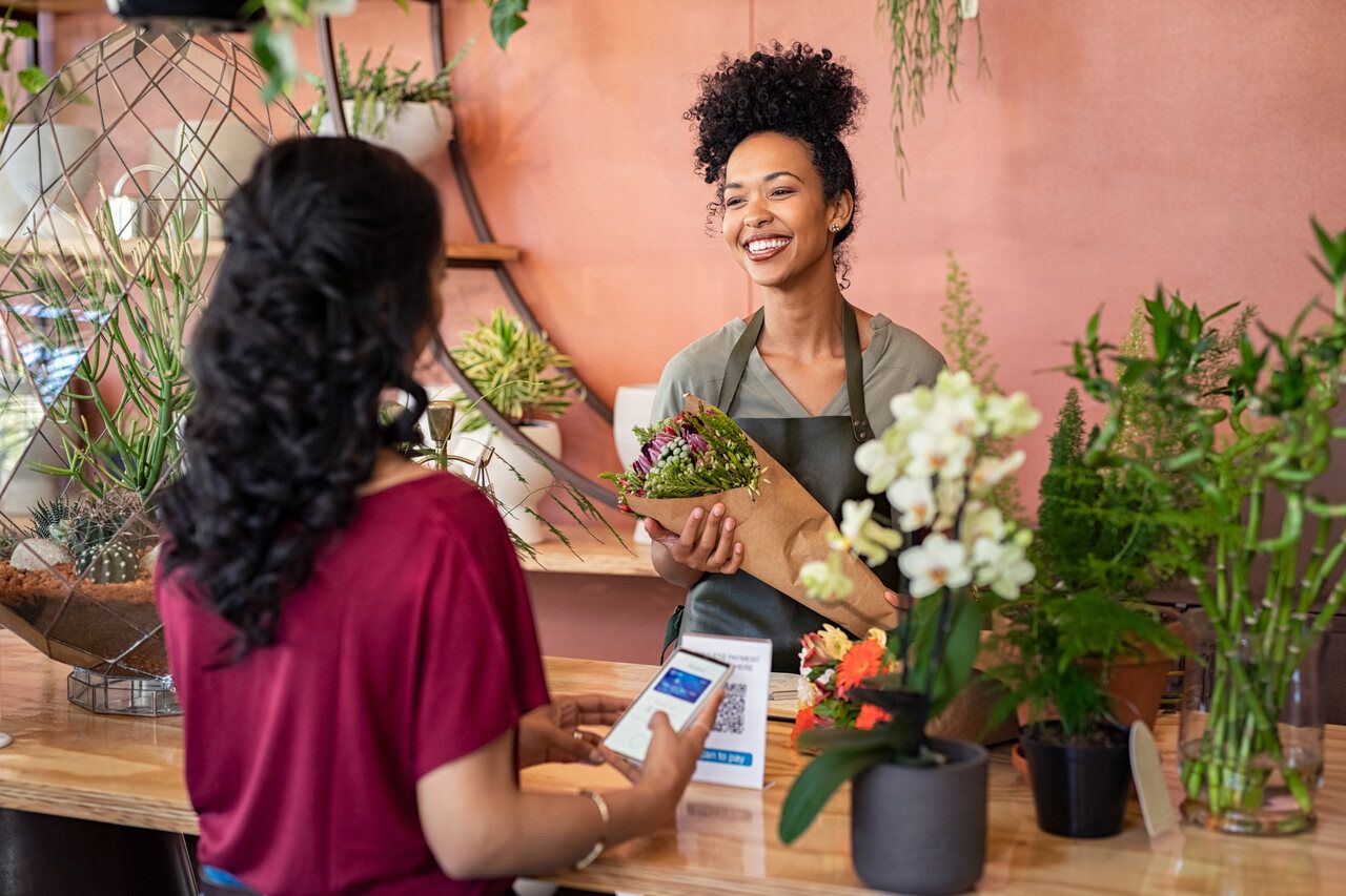 happy florist giving fresh bouquet to customer and a QR code on the counter