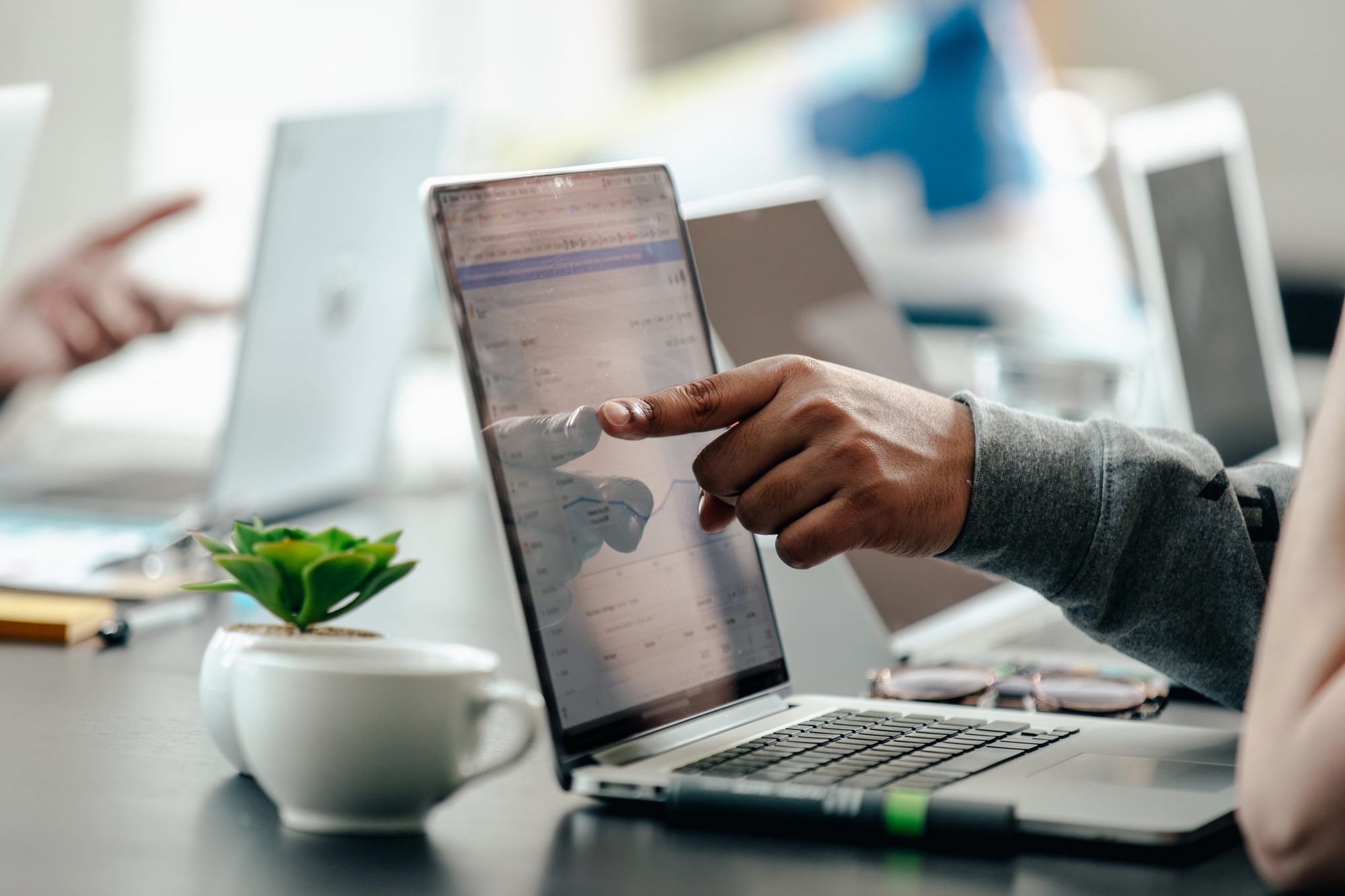 a finger pointing at a laptop screen displaying analytics