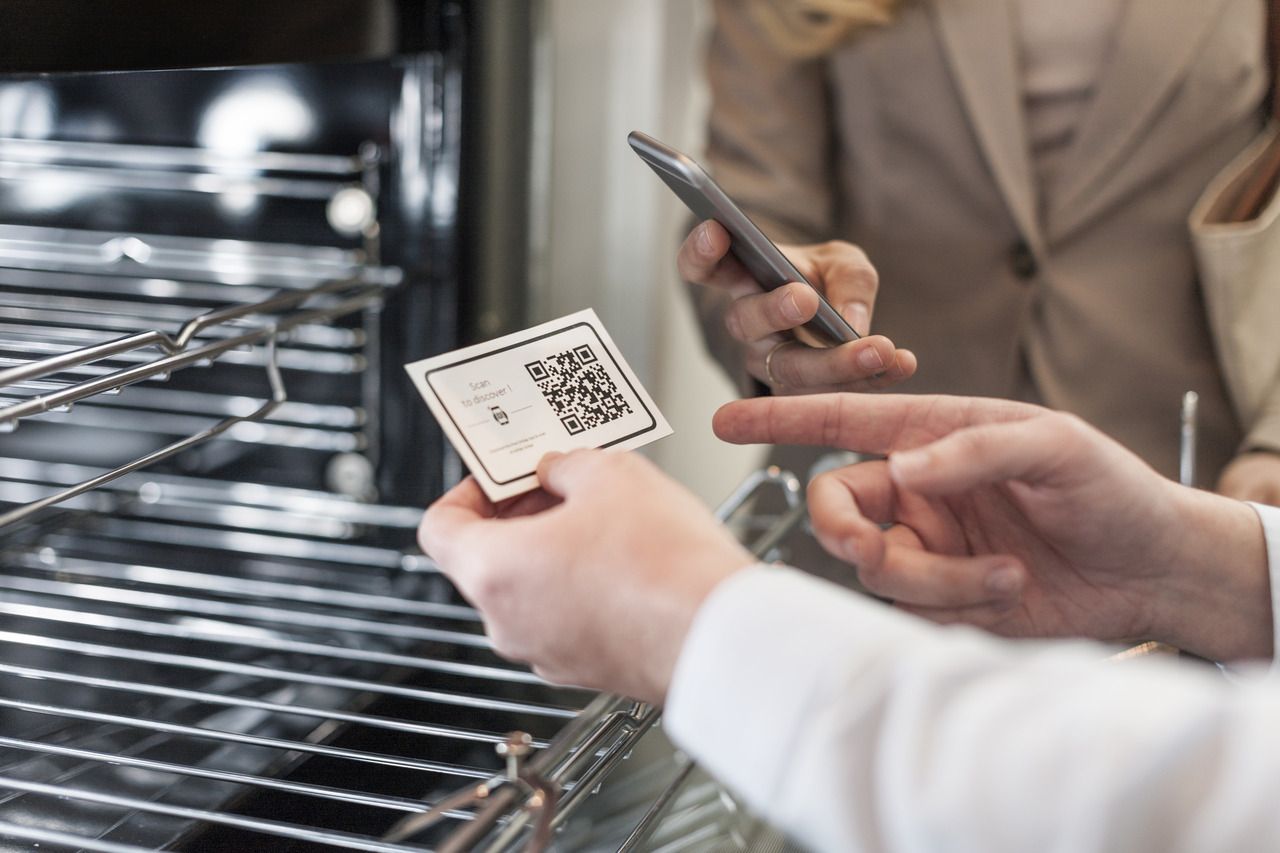 shop assistant and customer at oven with a business card with a QR code