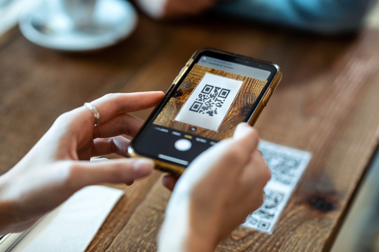 woman hands using an iPhone to scan a QR code on a table