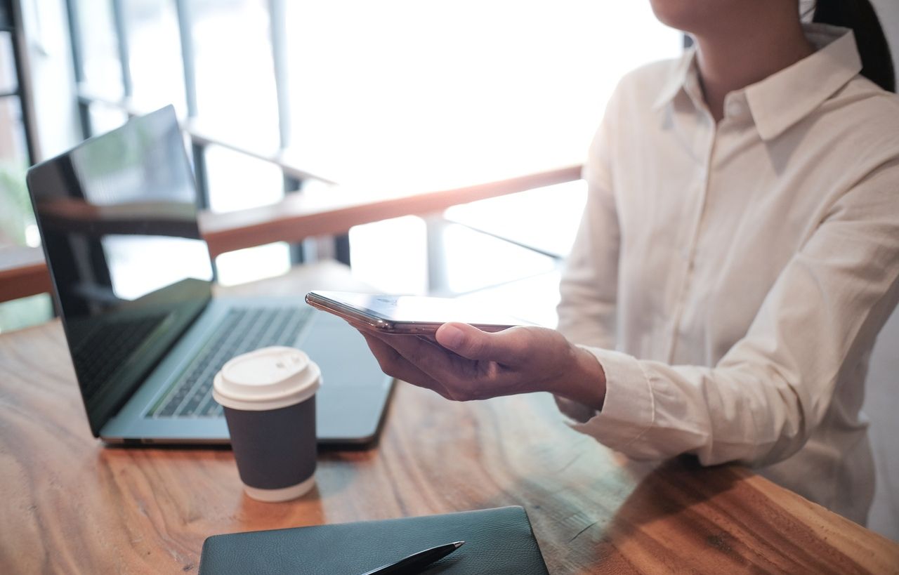 a woman scanning a QR code and a coffee & laptop at the background