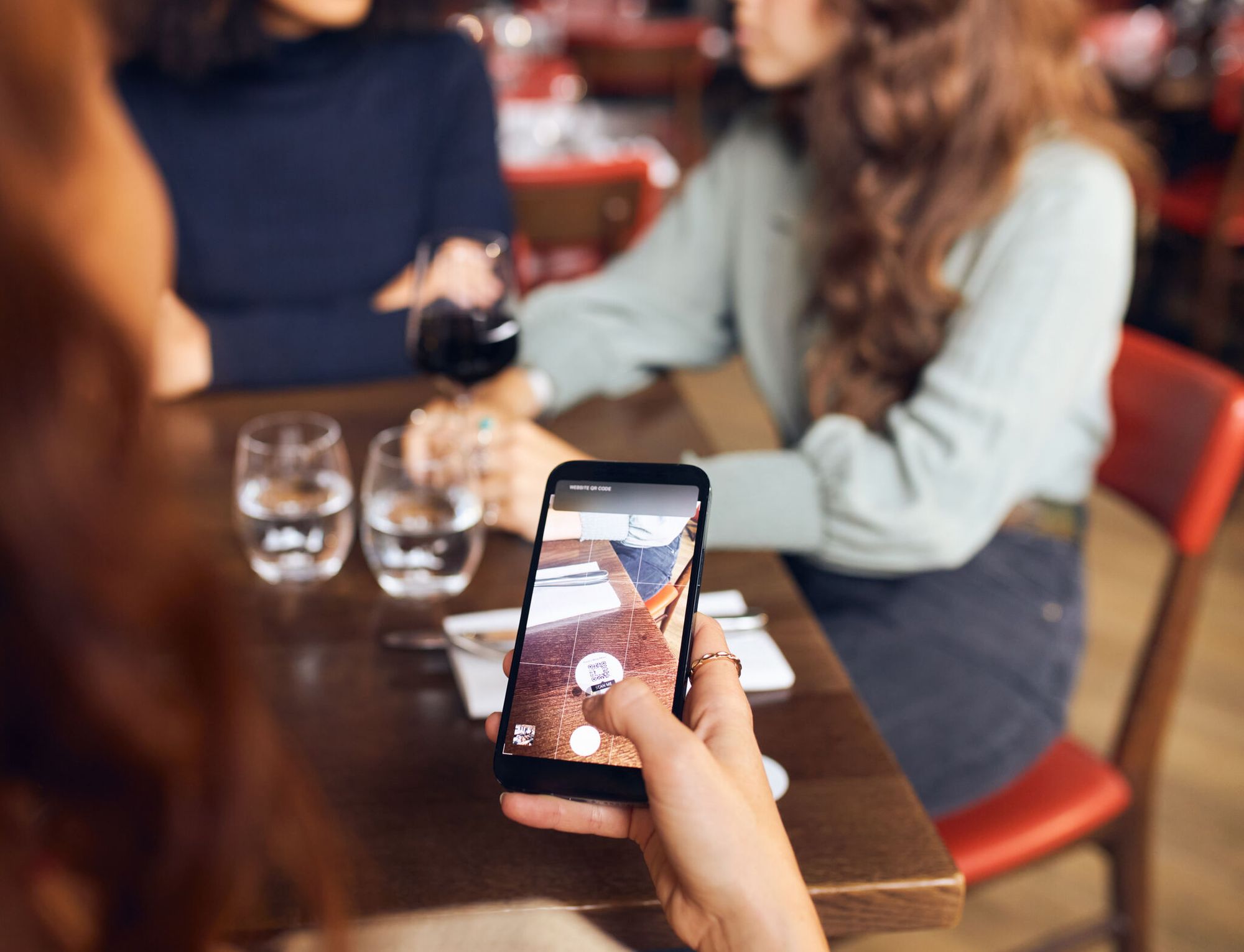 a woman scanning a QR code on a restaurant table