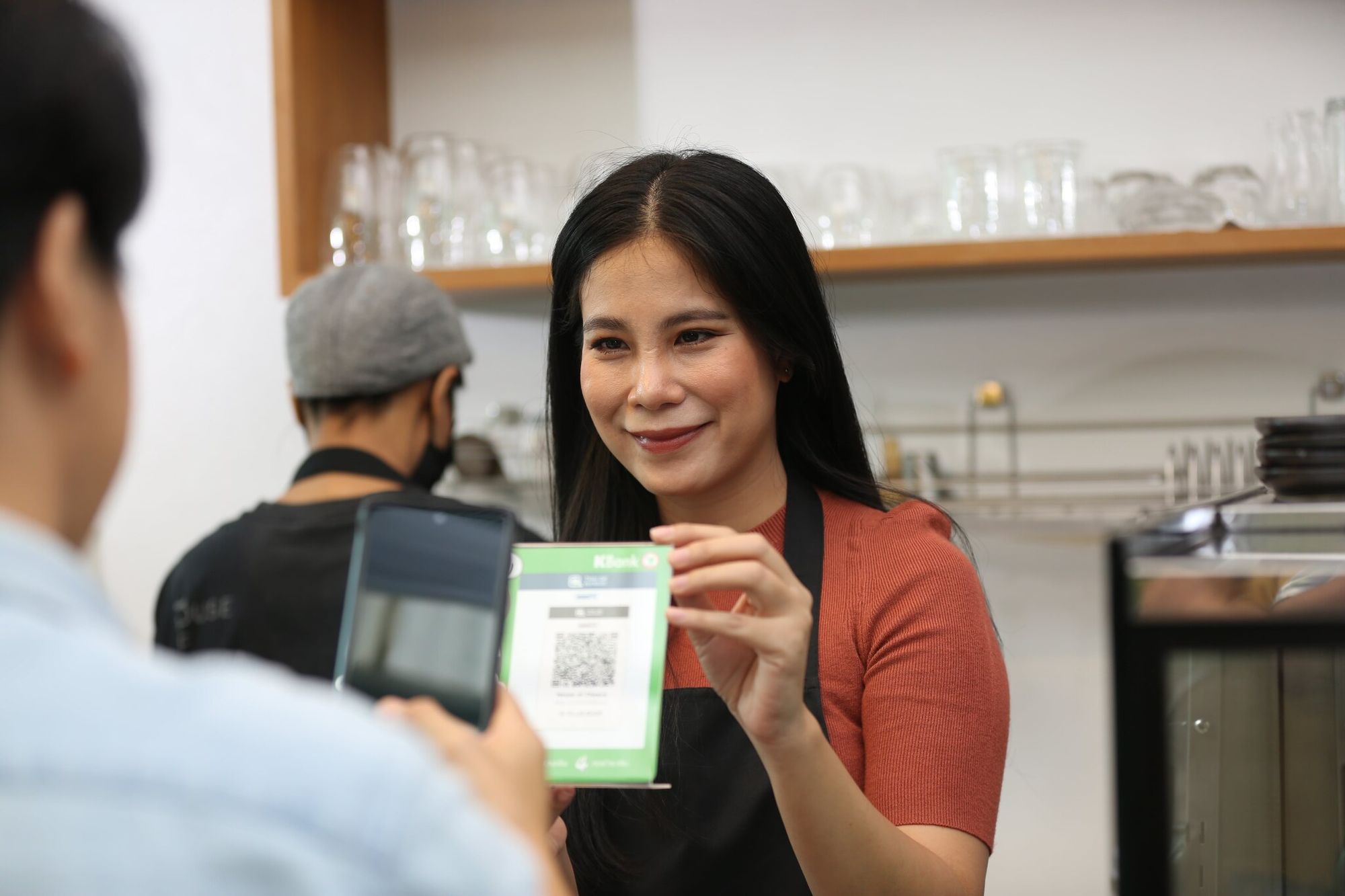 A man scanning a QR code and a woman smiling at a cafe