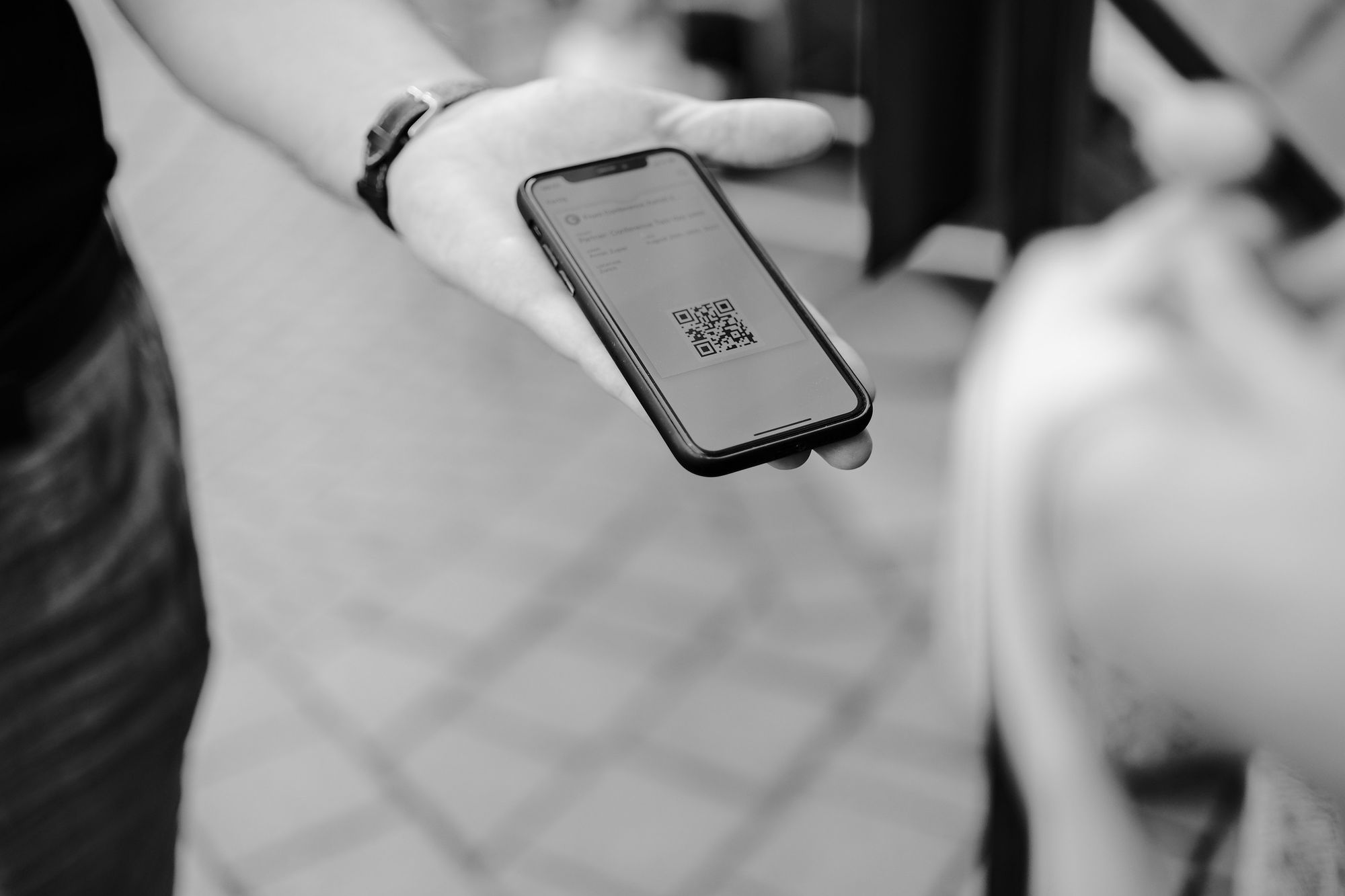 Black and white image of a person holding a phone with a QR code