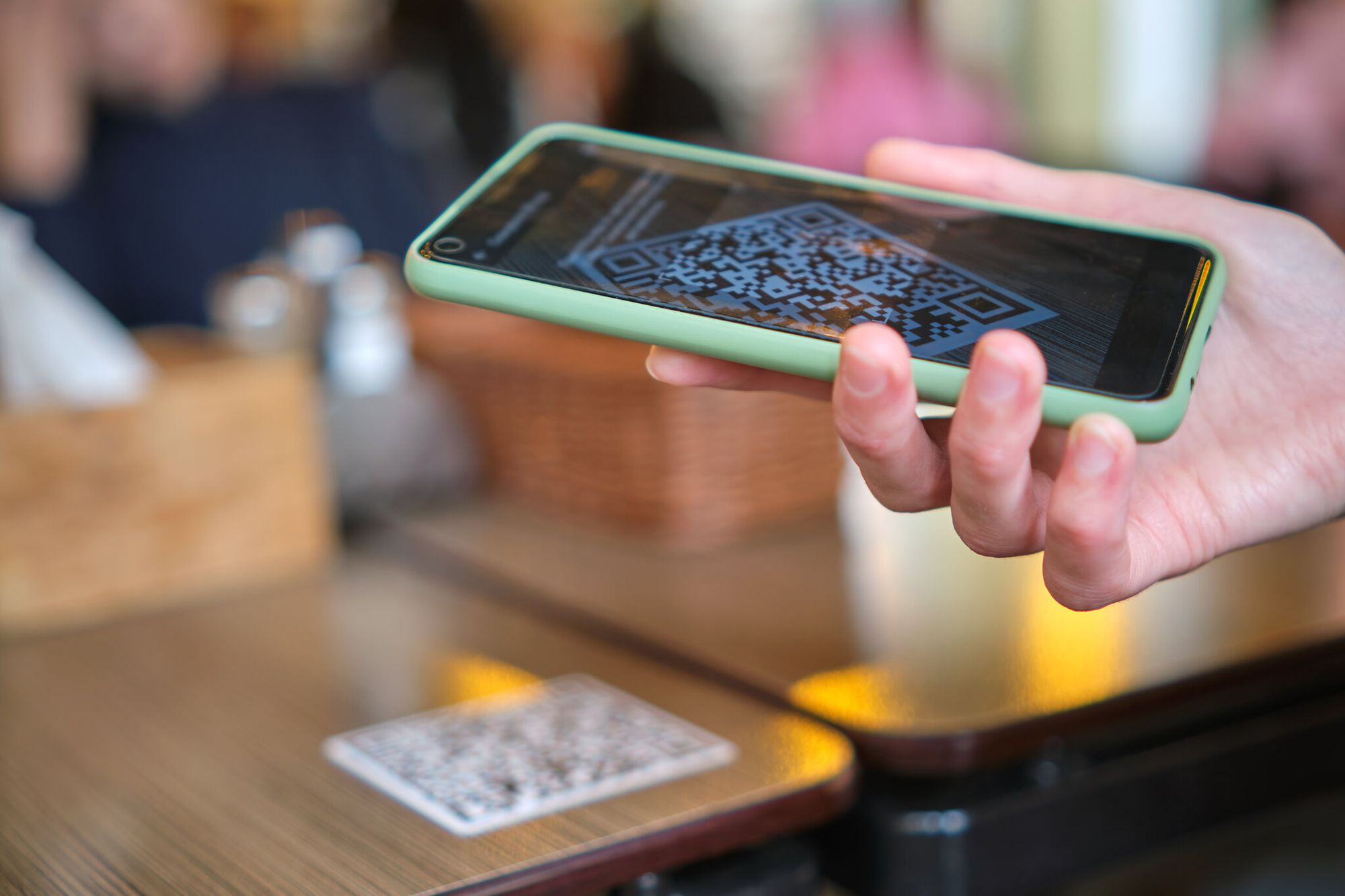 Close-up of a hand scanning a QR code on a table