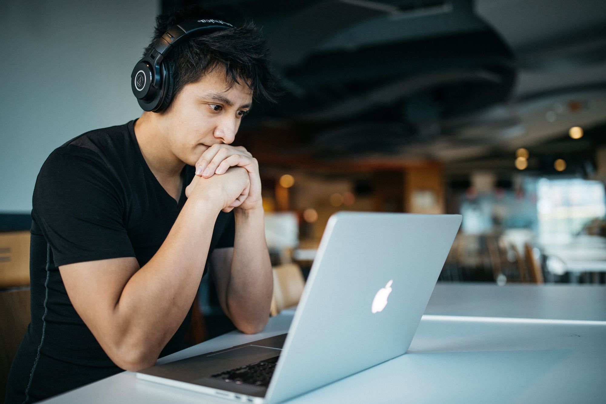A man wearing headphones and checking a laptop screen