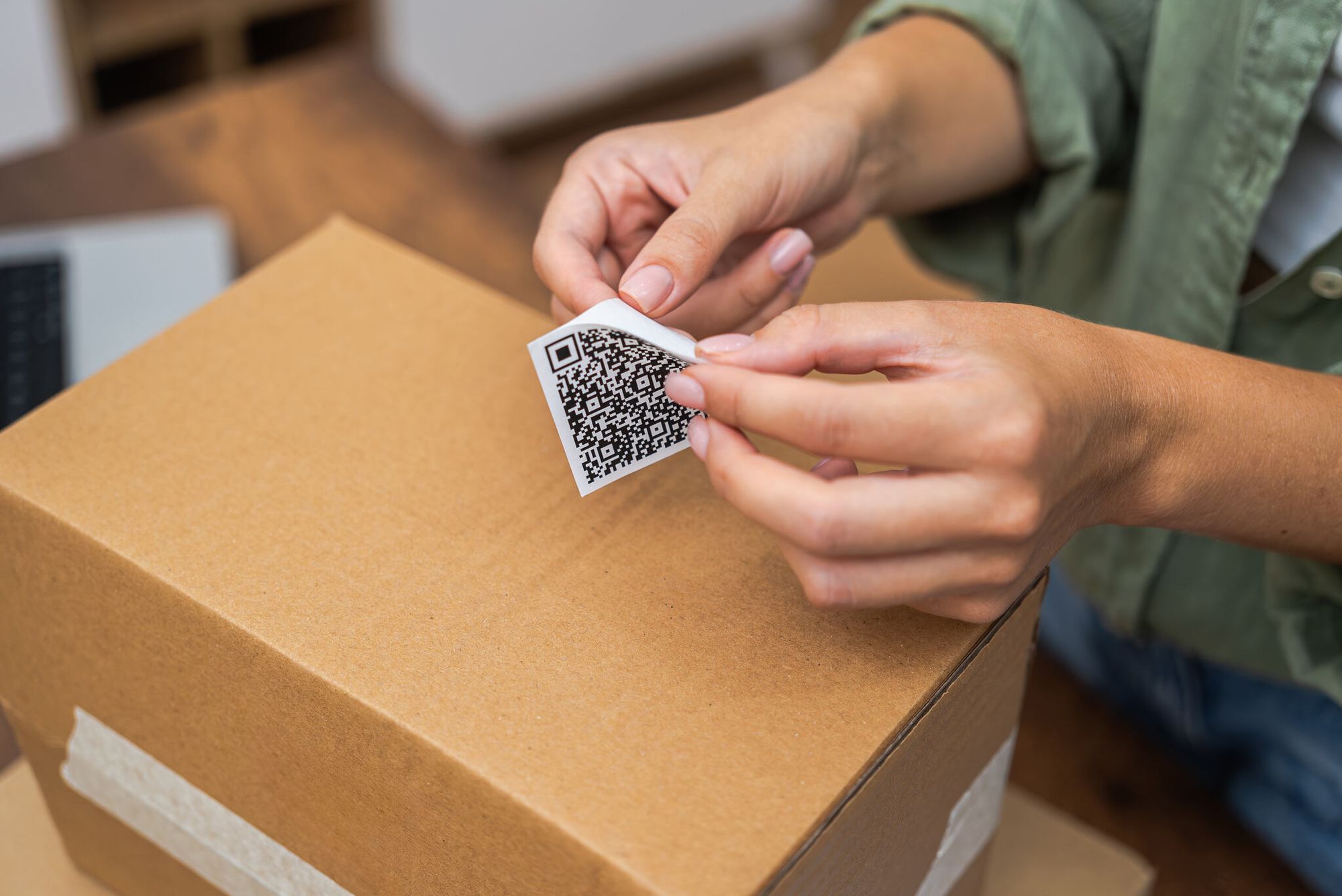 Woman's hands and a QR code sticker on a package