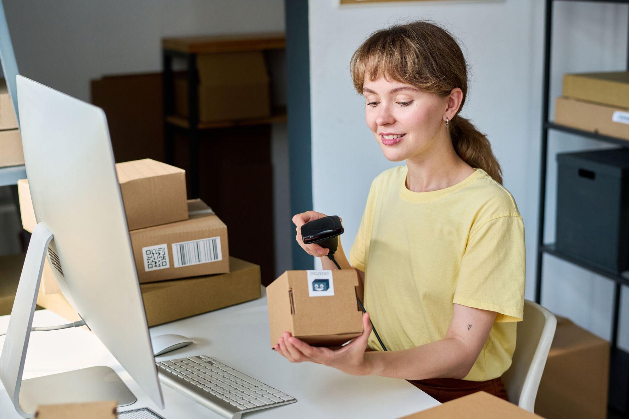 Young smiling woman scanning a packed box with a QR code