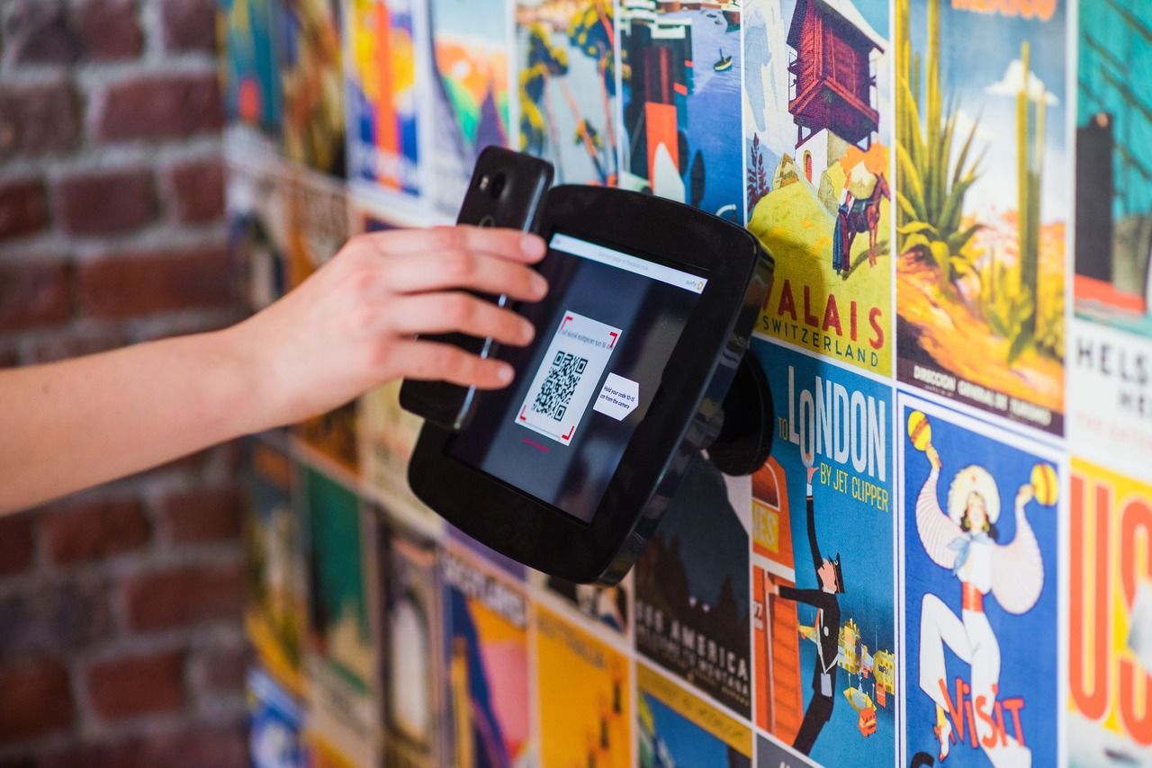 A hand scanning a QR code with a background featuring posters