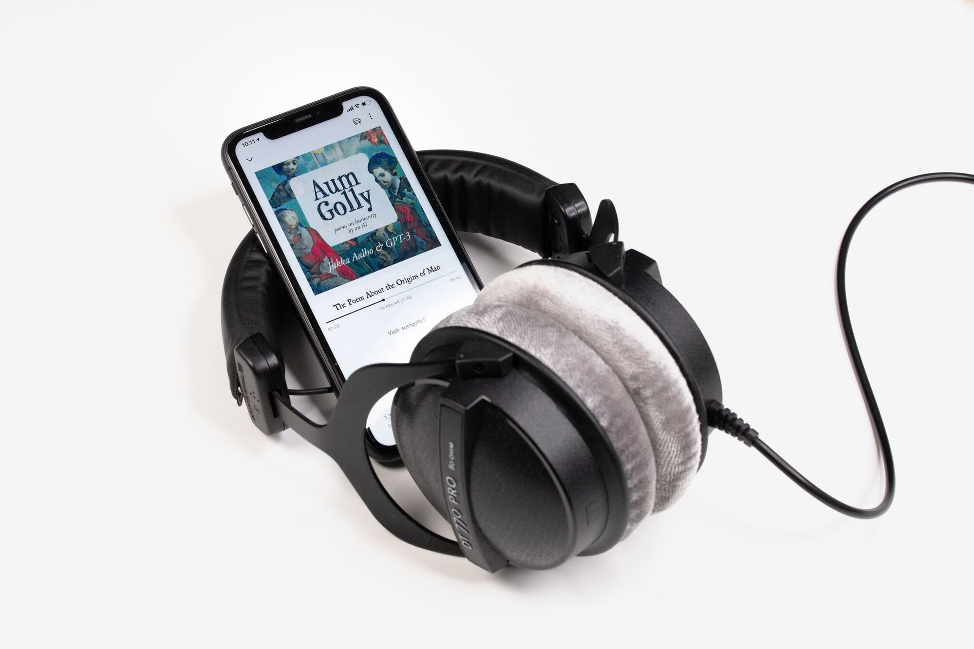 Black headphones and a phone displaying an audiobook