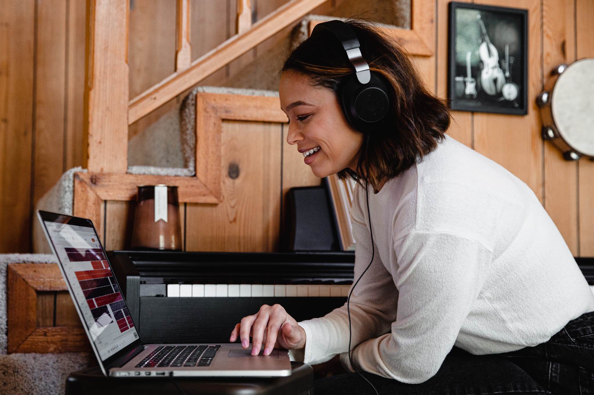 A woman wearing headphones and checking a laptop screen