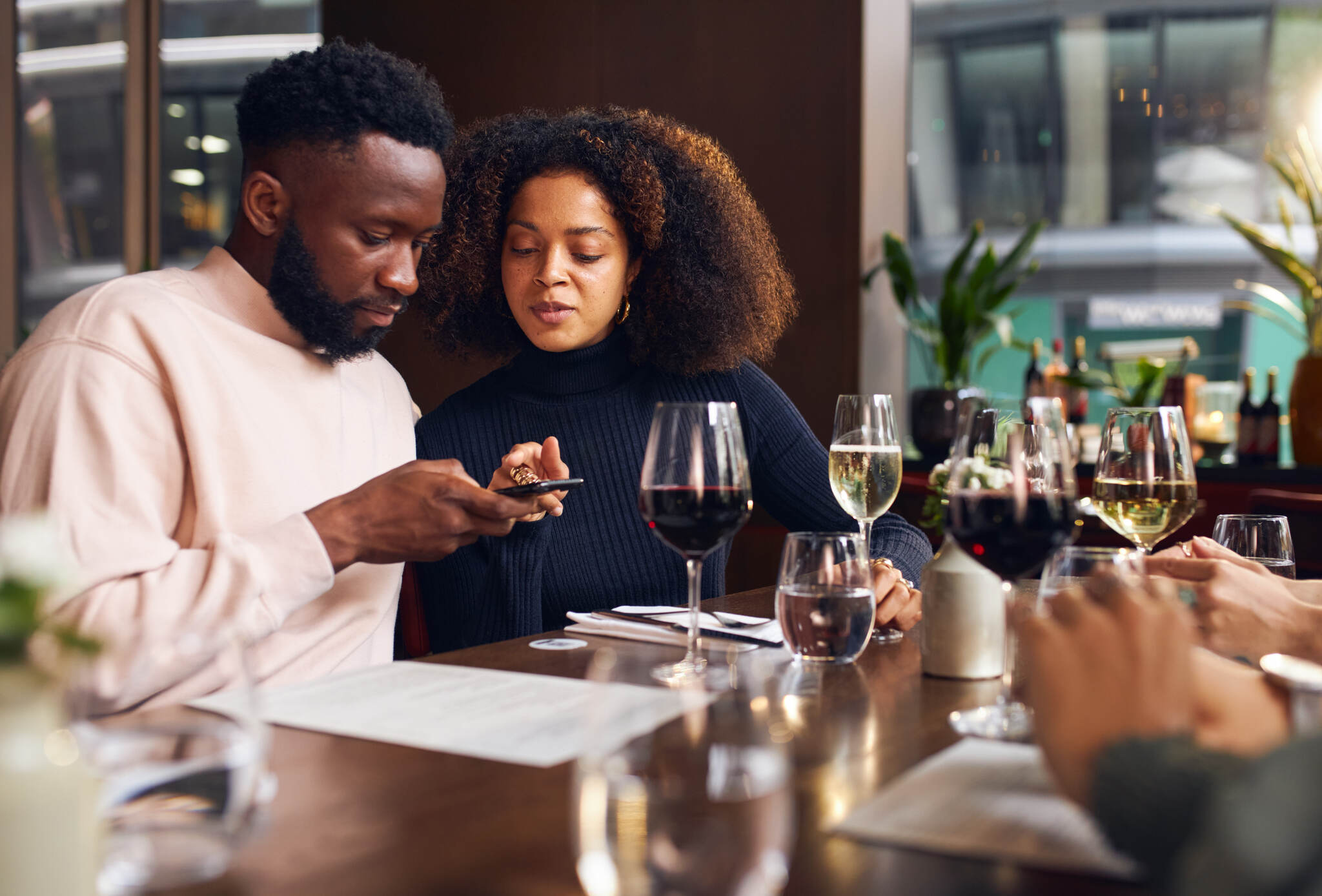 A young couple ordering on a phone in a wine bar 
