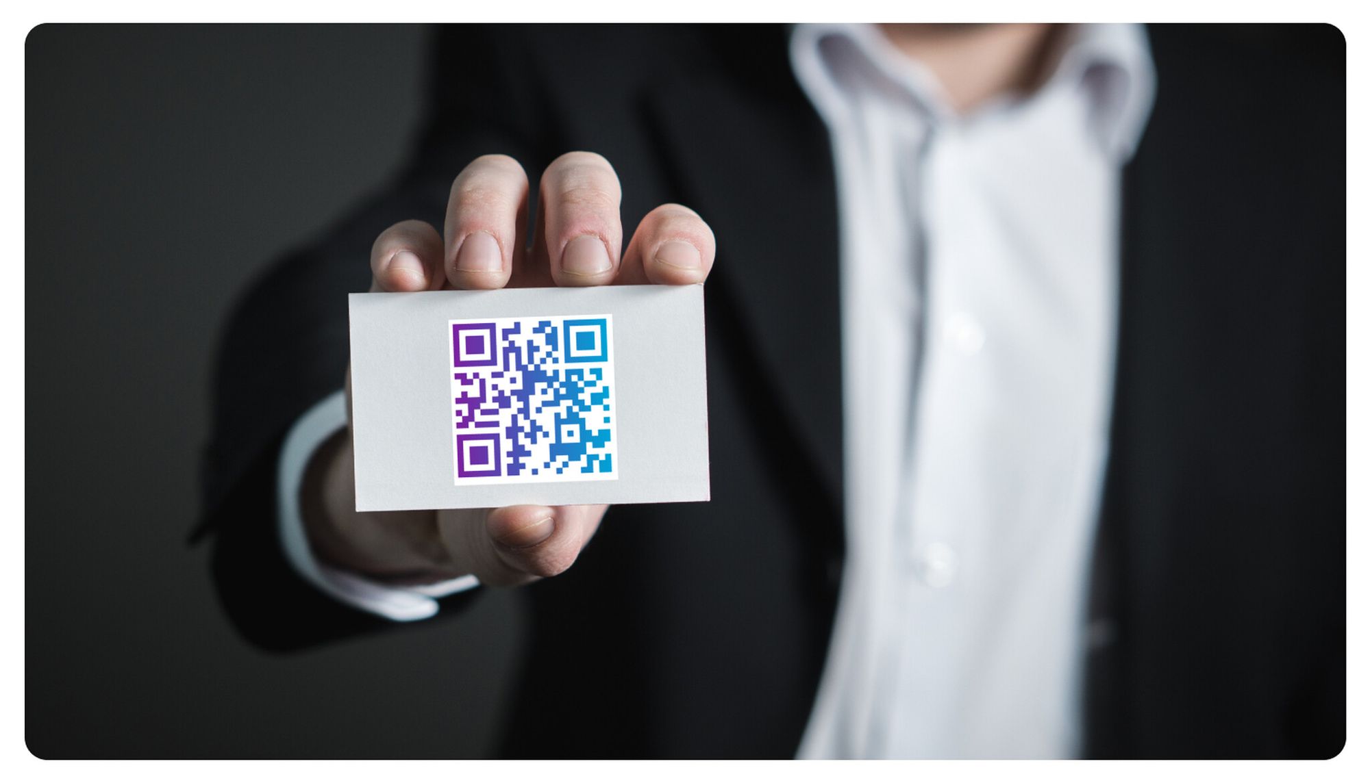 A man wearing a jacket and shirt displaying a card with a QR code