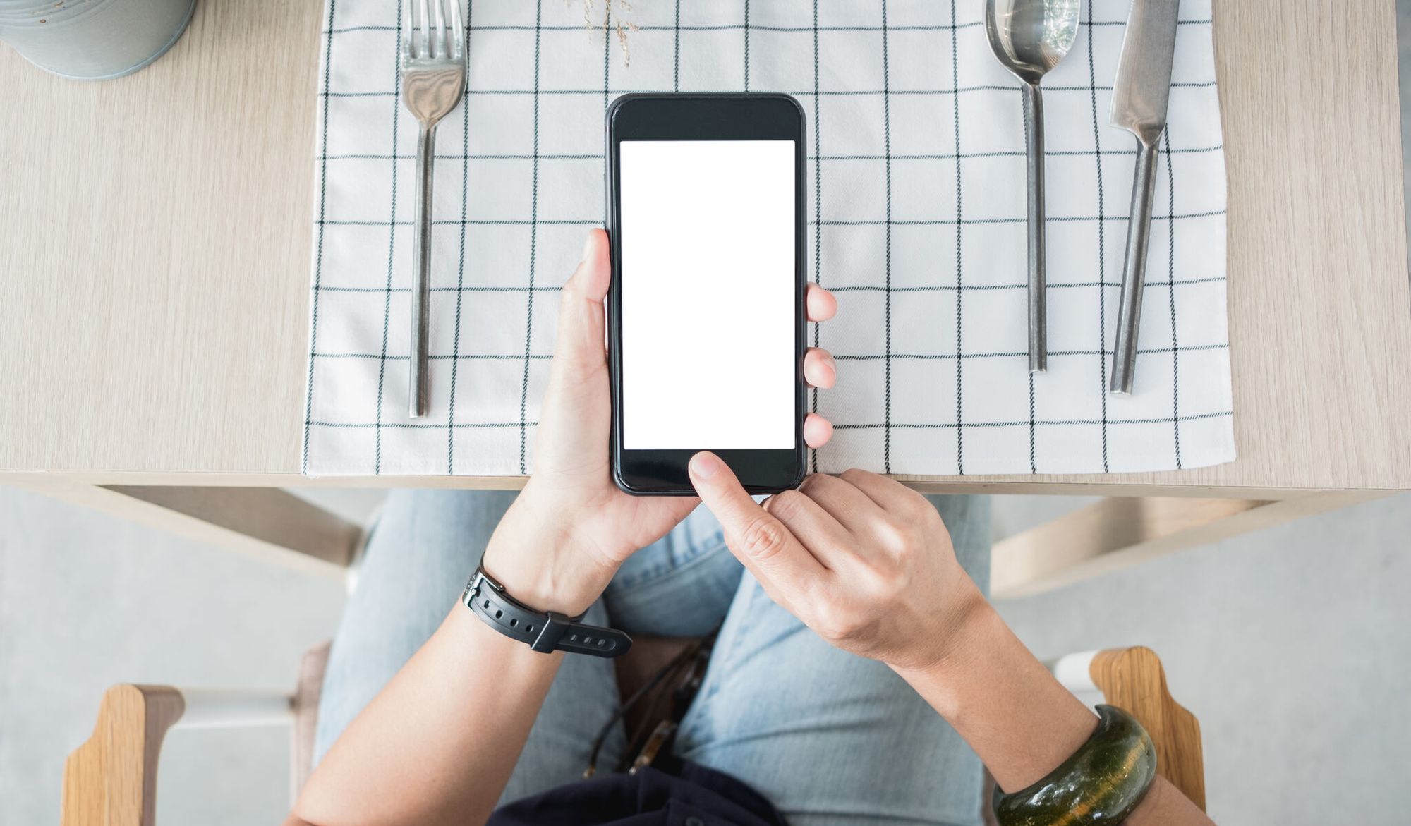 top view of a person using mobile order menu at restaurant