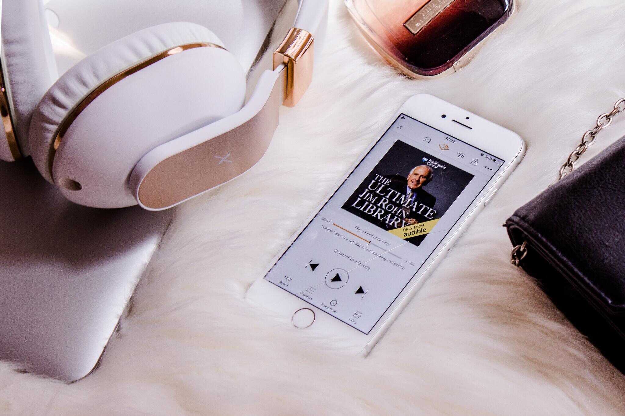 An iPhone displaying an audiobook with headphones next to it